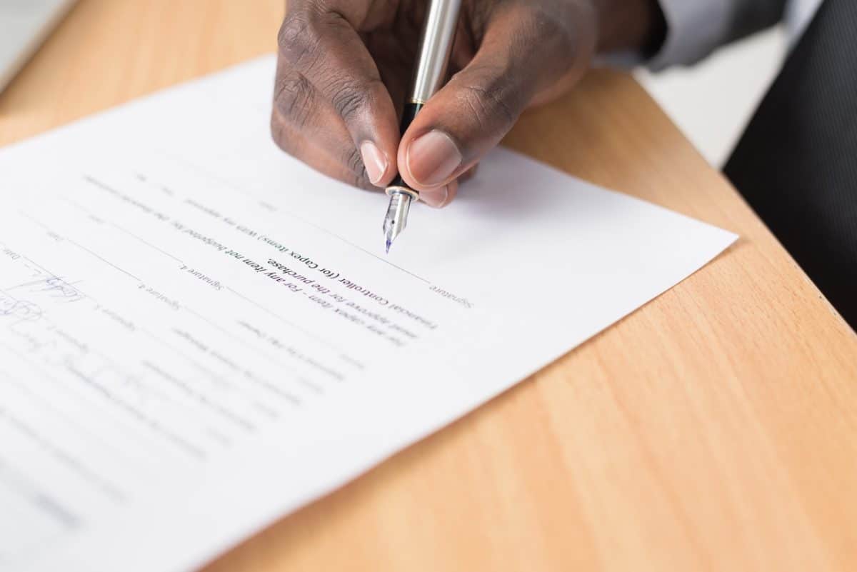 Hand holding pen and signing paperwork