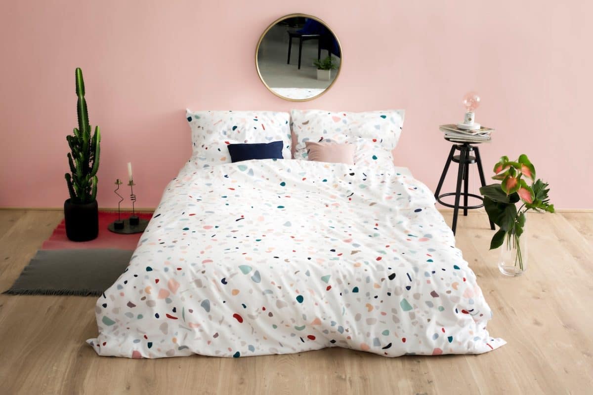 white bedspread with polka dots on bed in middle of pink room