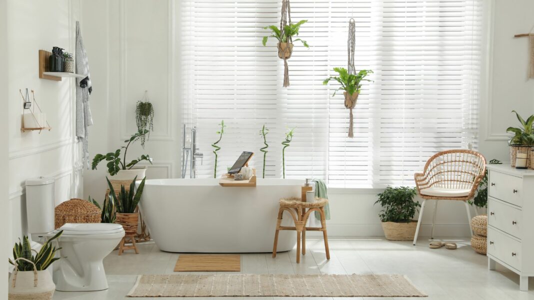 Stylish white tub and green houseplants in bathroom.