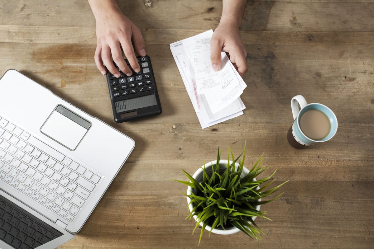 Hands holding bills and paying bills on computer