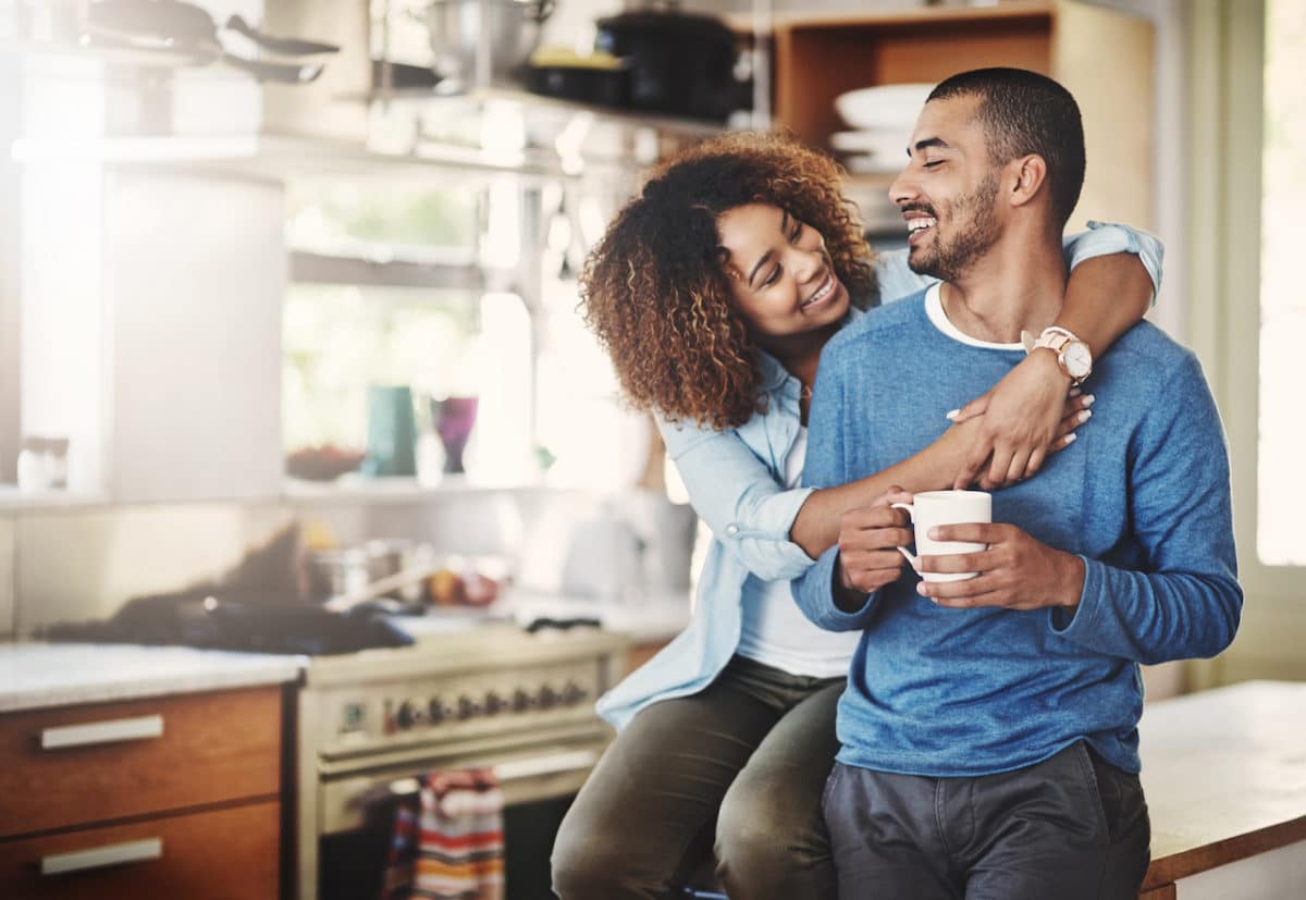 young couple in kitchen hugging each other and smiling