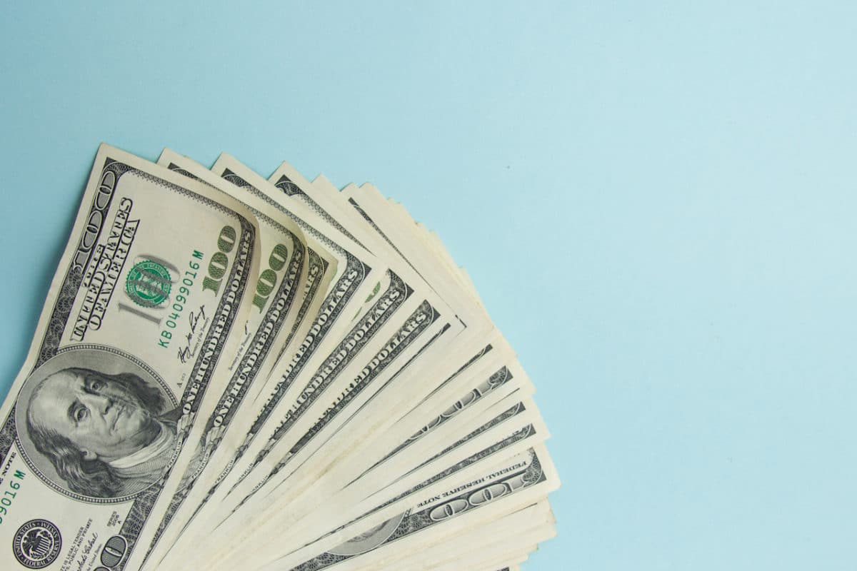 one hundred dollar bills spread out on blue background