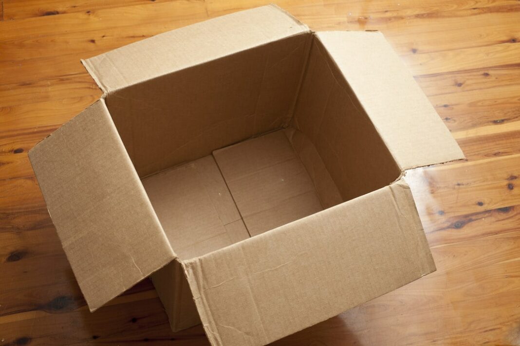 Empty Cardboard Box with Open Flaps on Wood Floor