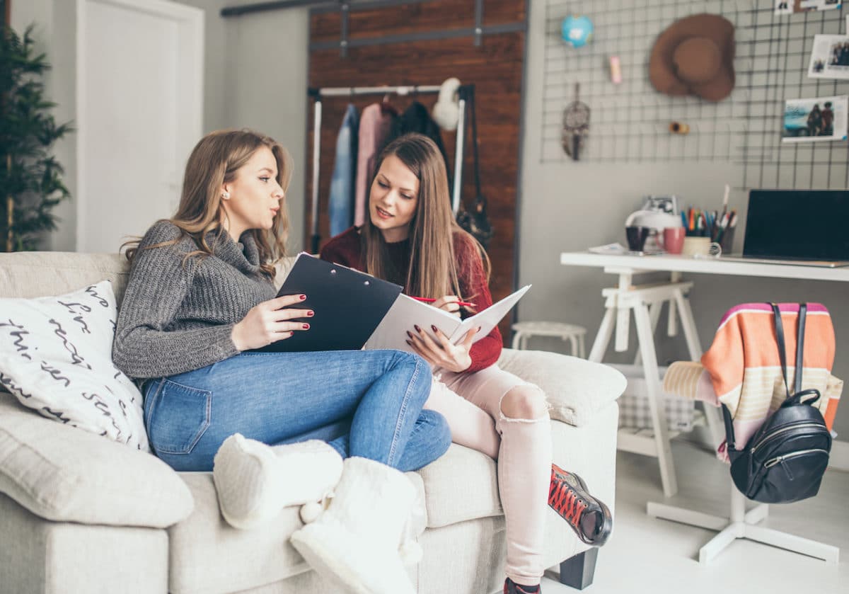 Two women talking and lounging on couch in apartment