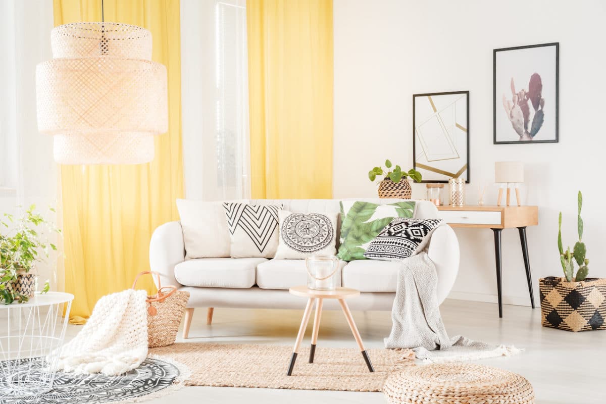 chic apartment with white couch, yellow curtains, rug, and pillows