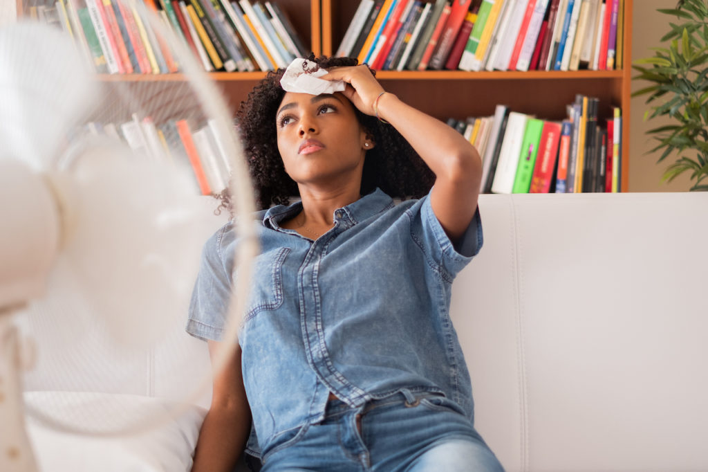 woman sweating indoors with fan on her