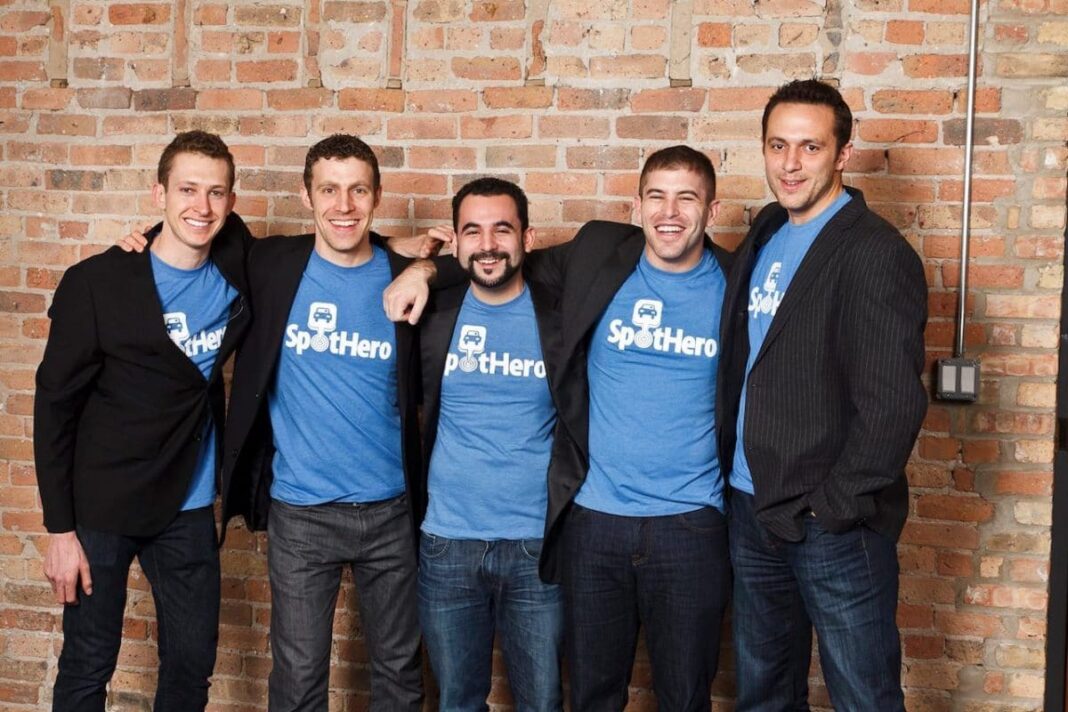 5 men in spothero shirts posing in front of brick office wall