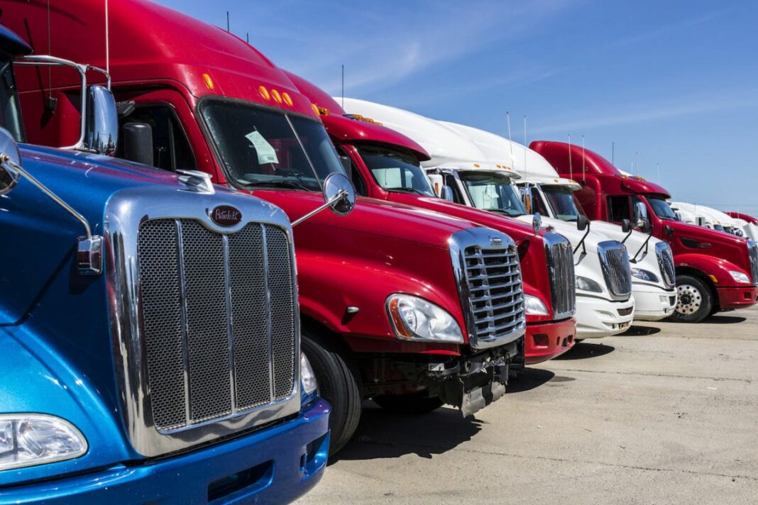 multi-colored semi trucks lined up in a row and parked