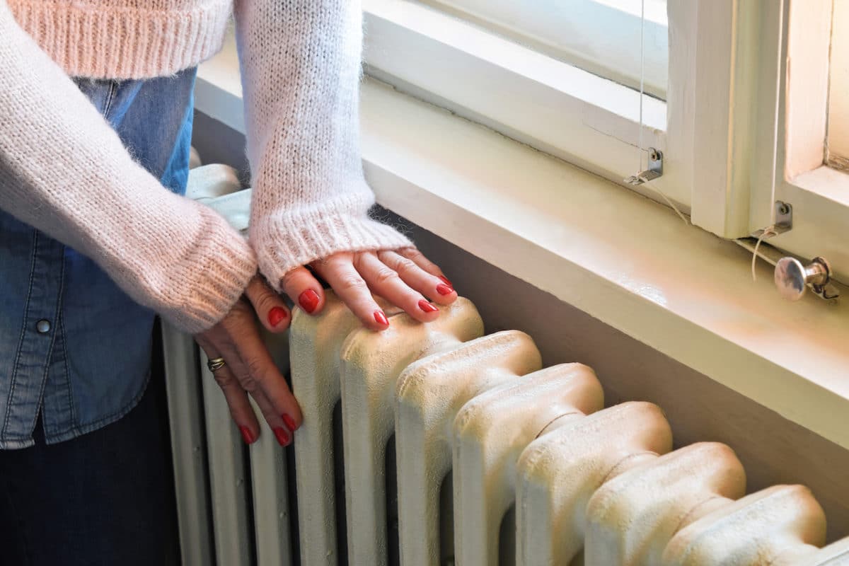 woman's hands on top of white heater in room