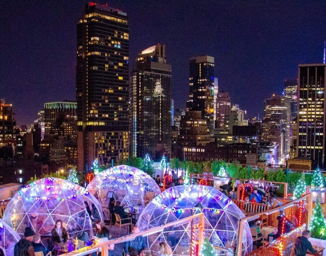 snow globes and christmas lights on rooftop with skyline in distance