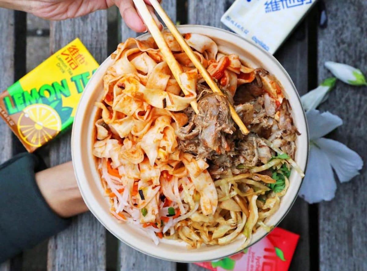 Bowl of noodles with beef and chopsticks digging in