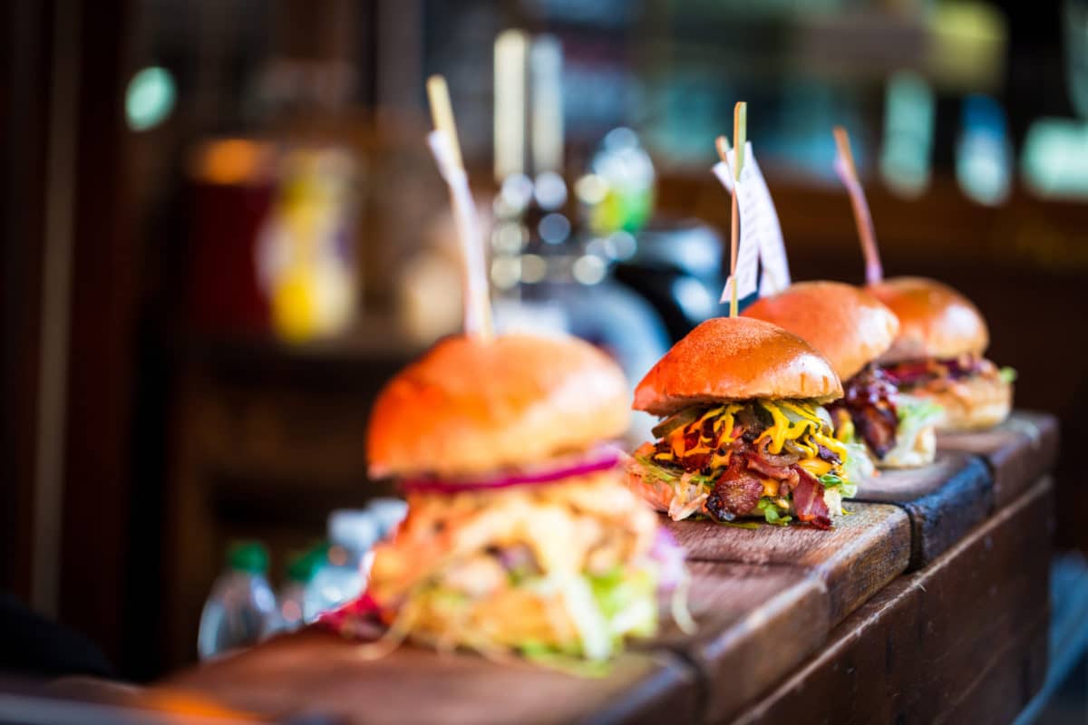 Close up of fresh flame grilled burgers displayed in a row at food market