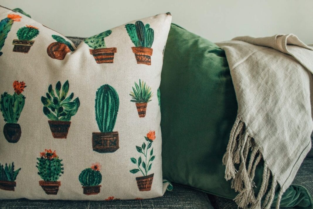 green pillow, cactus pillow, and beige blanket on couch 