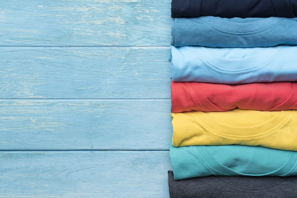 close up of rolled colorful clothes on blue wood table background