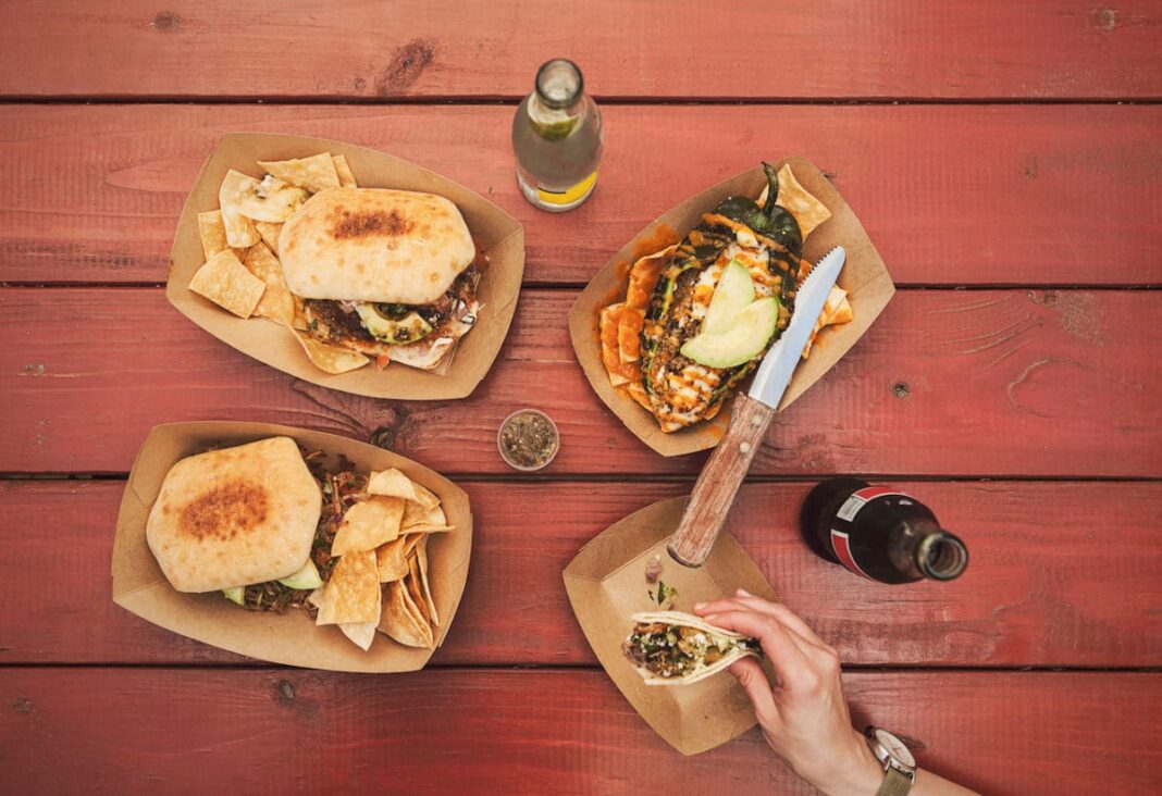 Table with food truck food with bottle of coke next to it