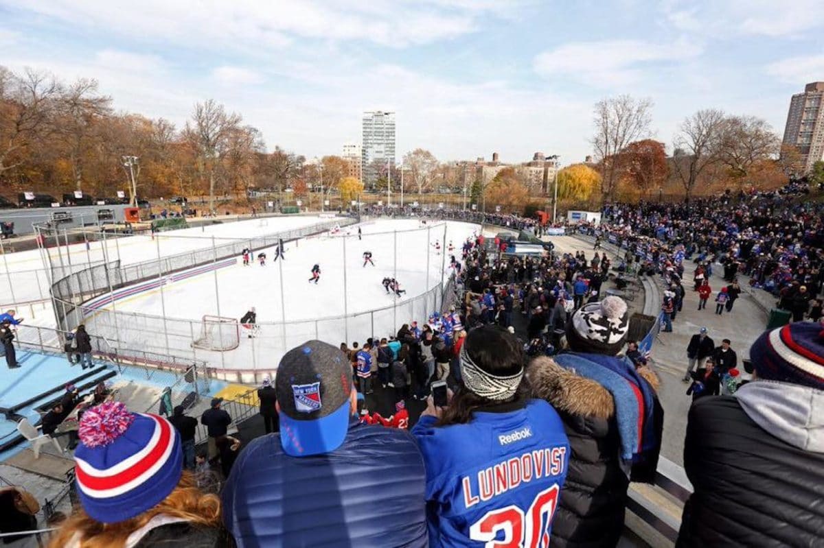 people in stands watching an amateur ice hockey game at lasker rink