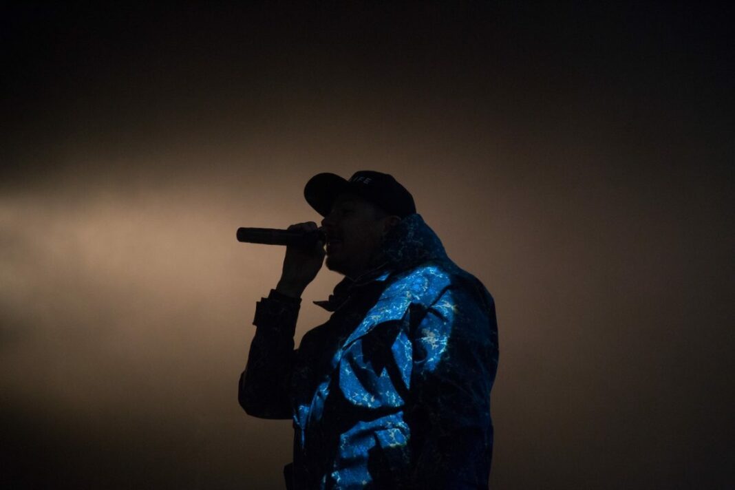 dark image and low lighting of rapper on stage