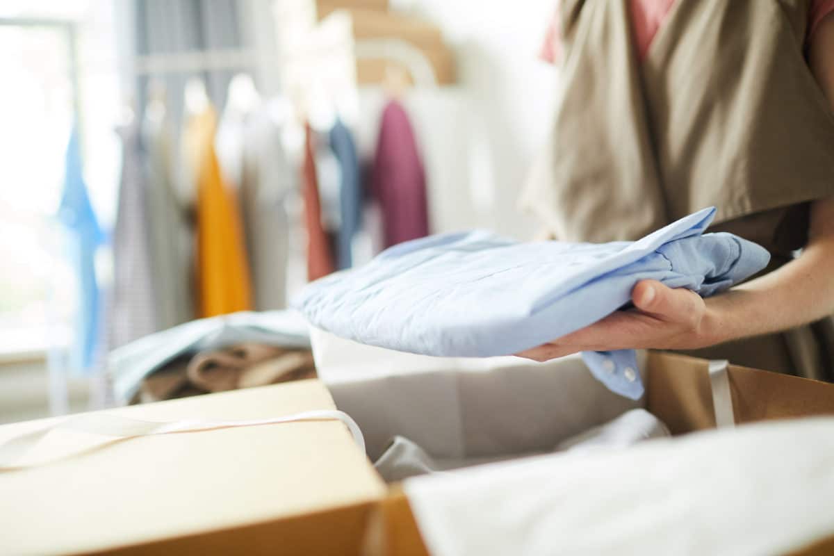 Person putting folded shirt into a box