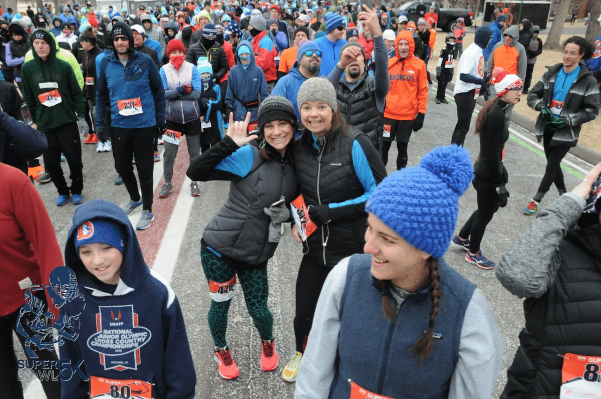 two women waving in a sea of runners waiting for the 5K to begin