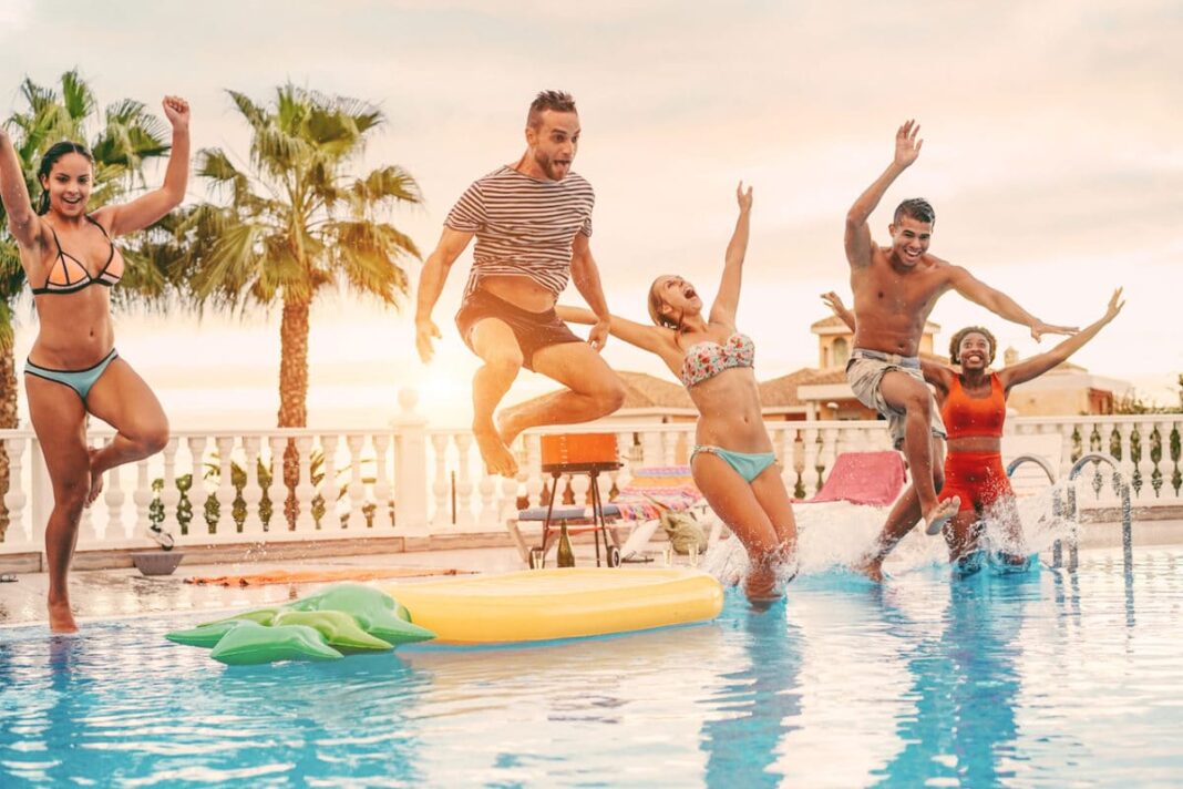 A group of friends jumping into a pool on a hot day