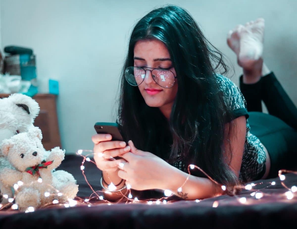 woman laying on stomach and texting friends 