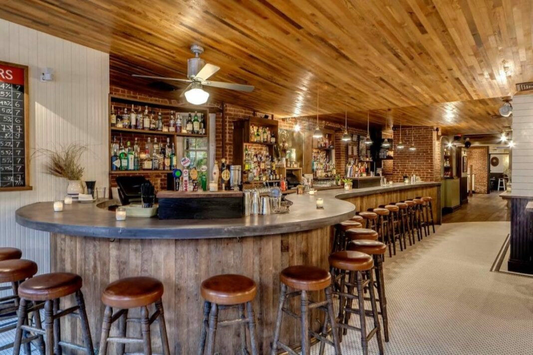 wide shot of bar interior with barstools and liquor on shelves