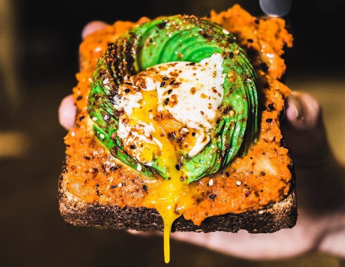close up of avocado toast with egg yolk dripping off of it