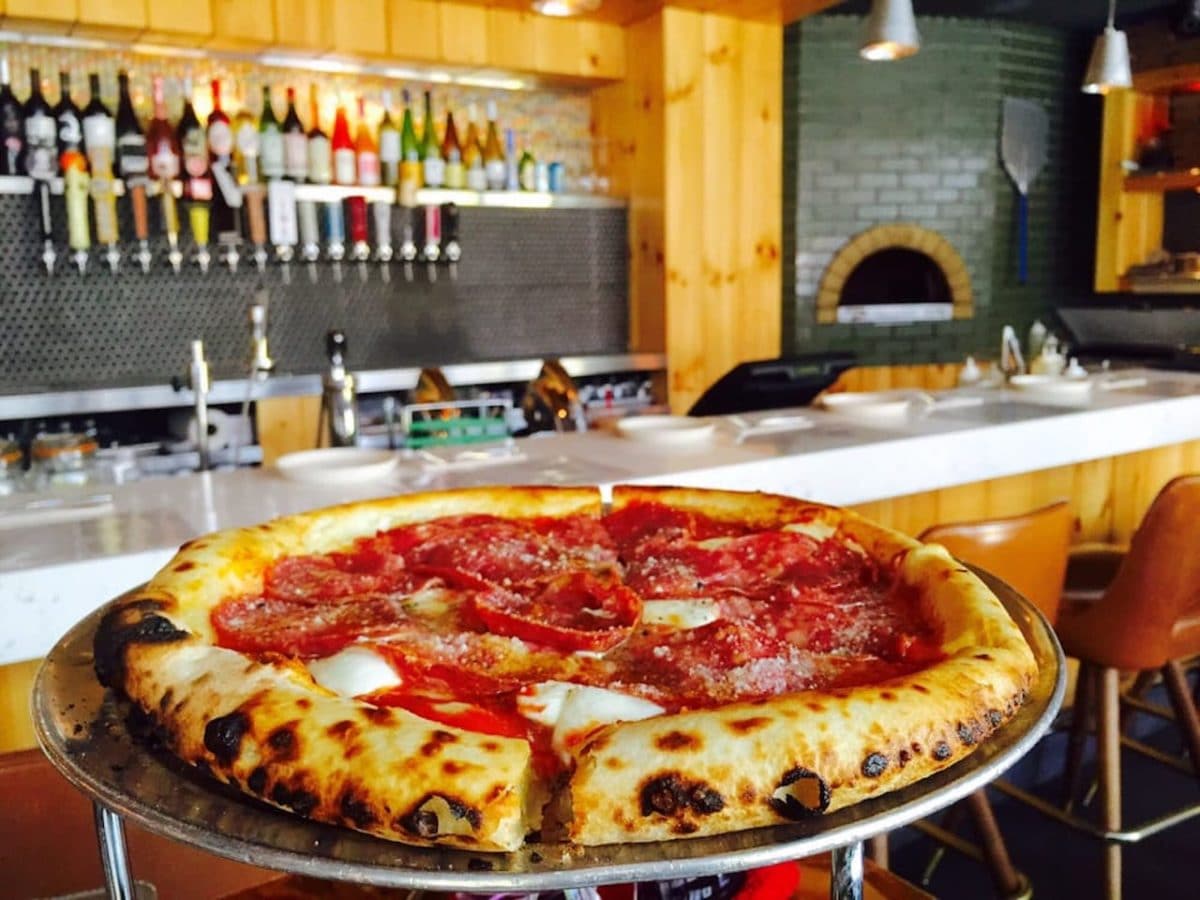 close up of pepperoni pizza on cooling rack with bar in the background