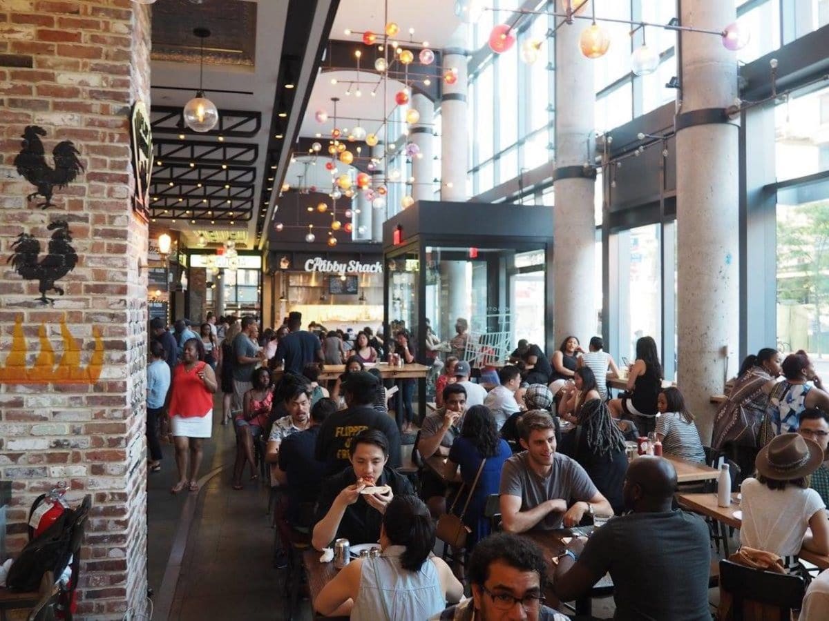 people sitting at tables in large, indoor space with high ceilings