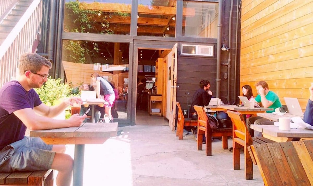outdoor patio of coffee shop with tables and chairs with people working
