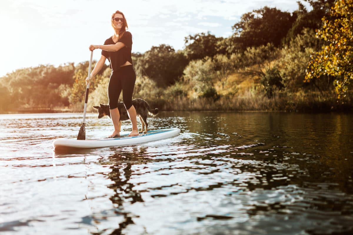 woman standing on paddleboard with dog 