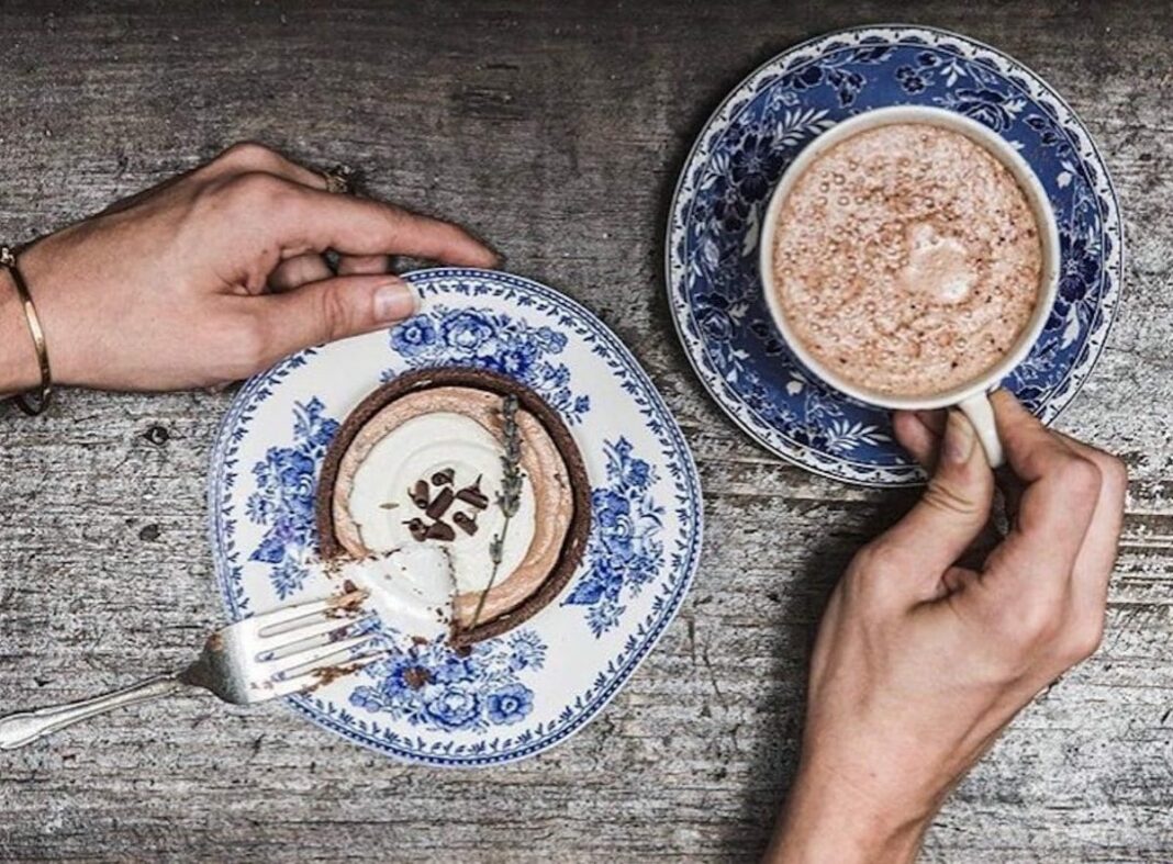 two hot chocolates on small saucers with two hands reaching for both