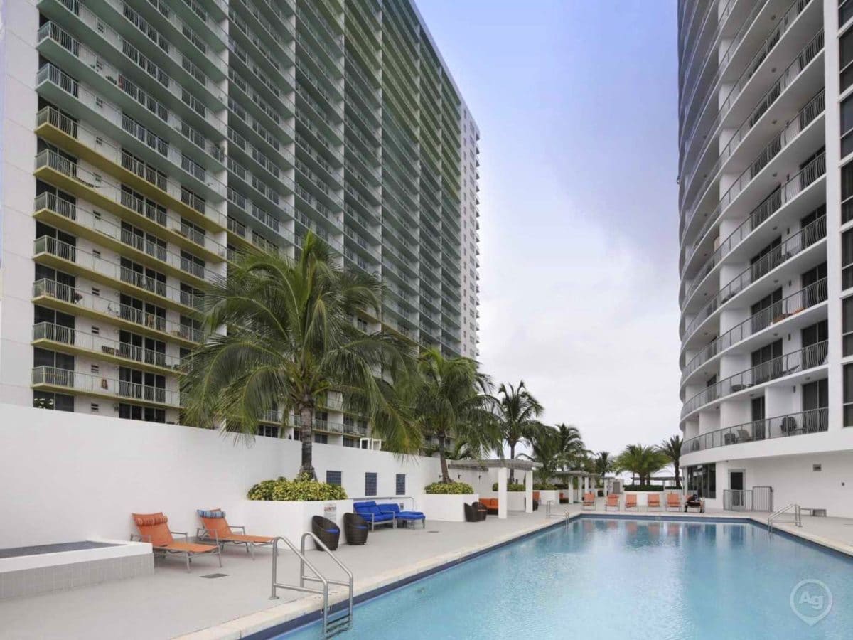 pool with chairs surrounding it and tall buildings on either side