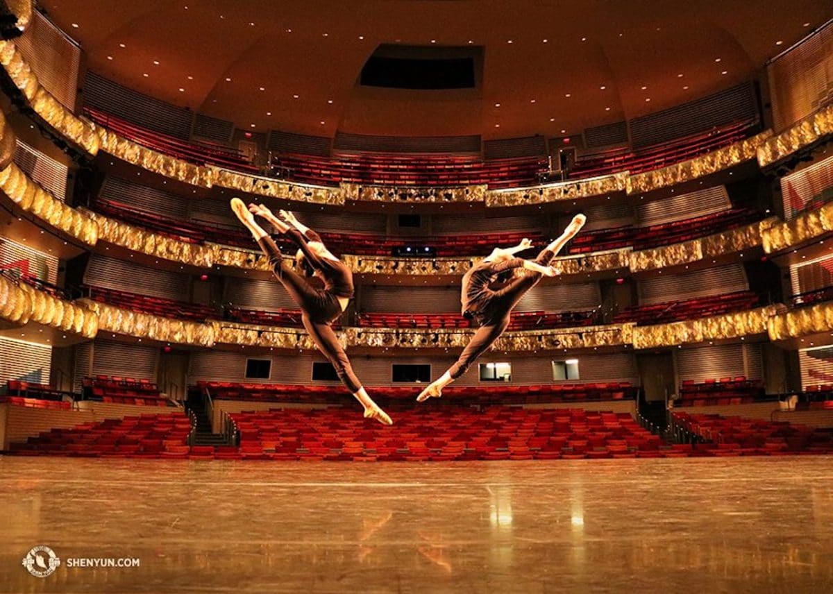 two female dancers performing on stage in large performance hall