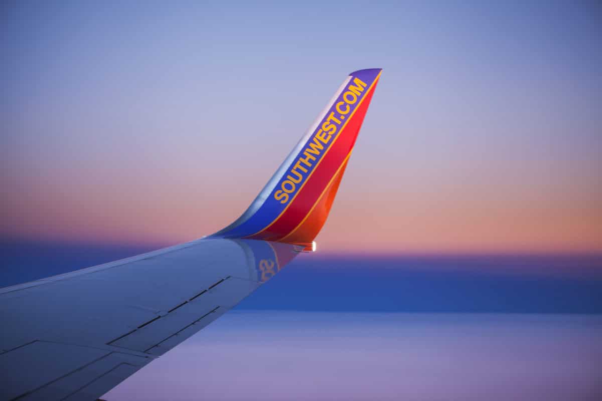 wing of southwest airplane with pink and purple sky in background