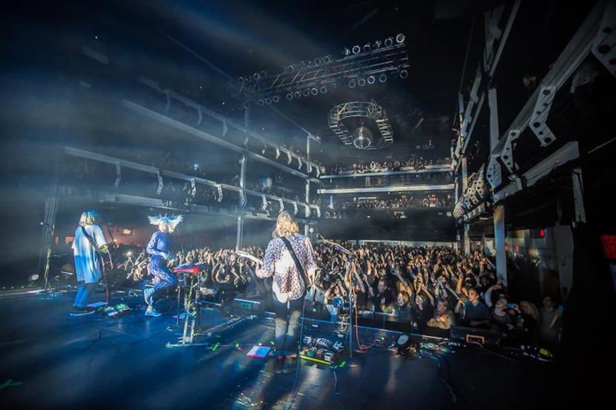 band on stage playing out to a full crowd inside venue