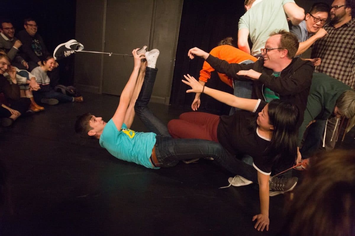 Stage with person on ground and others laughing at him