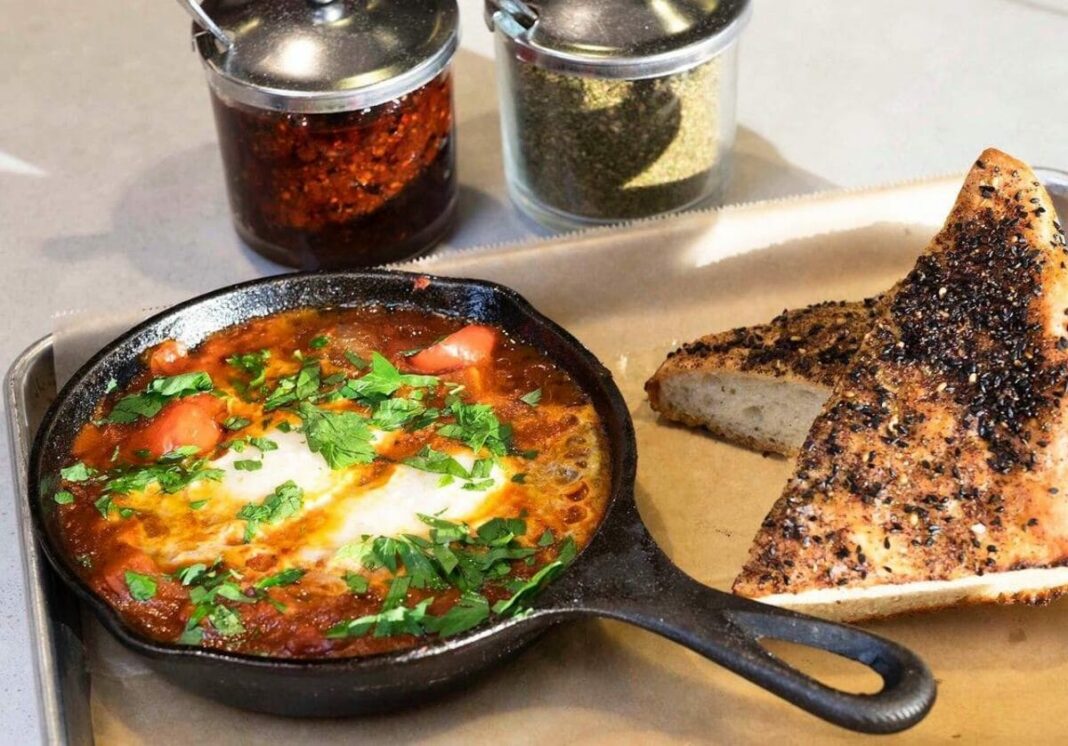 cast iron skillet with food in it and bread sitting next to it