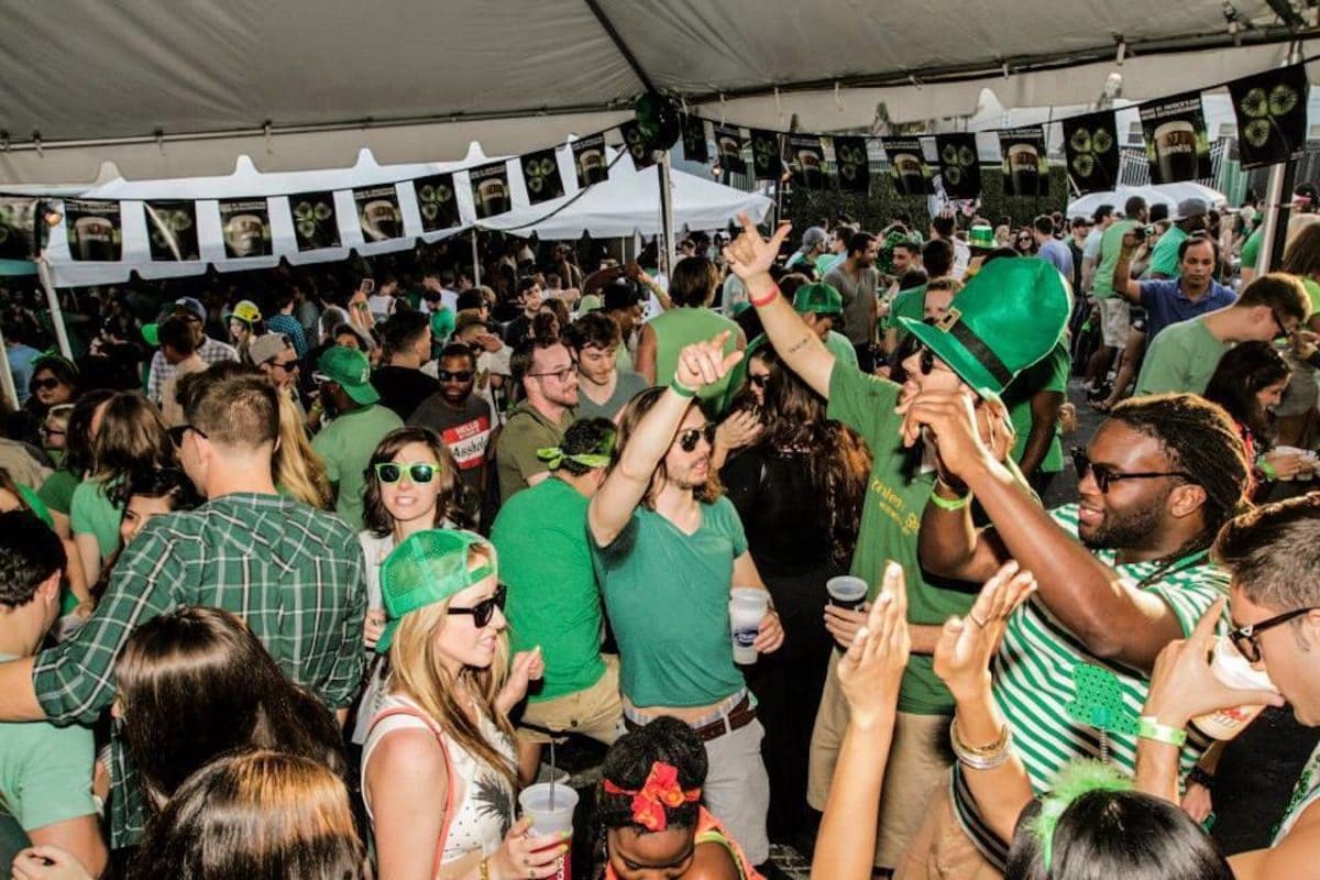 people dancing under large tent, drinking, and smiling