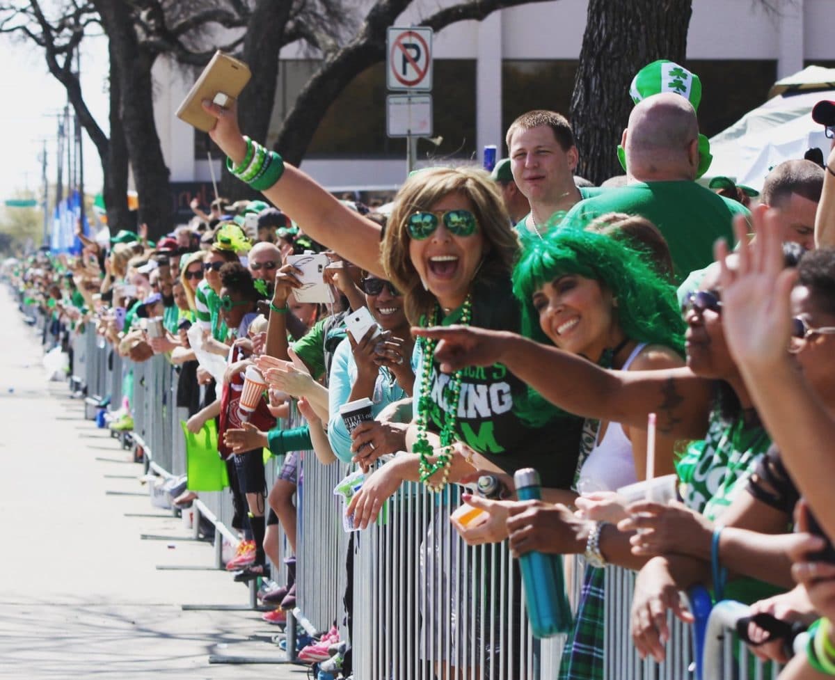 people cheering behind small fence during st. patrick's day parade