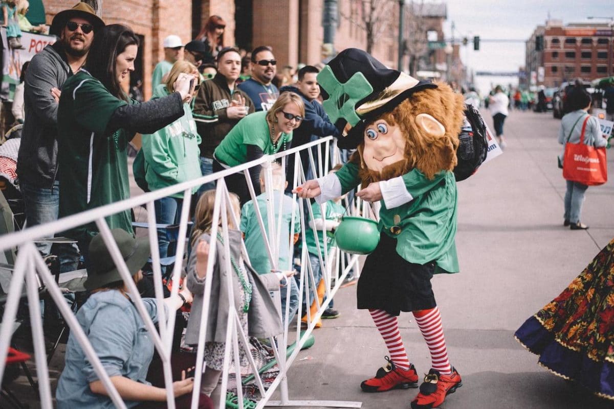 person in leprechaun costume handing out candy to people watching the parade