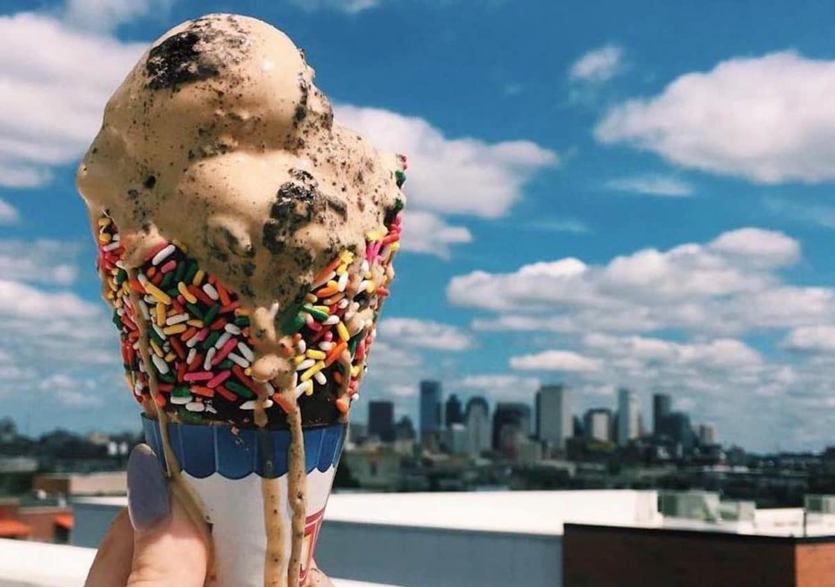 ice cream cone with sprinkles held up to the boston skyline