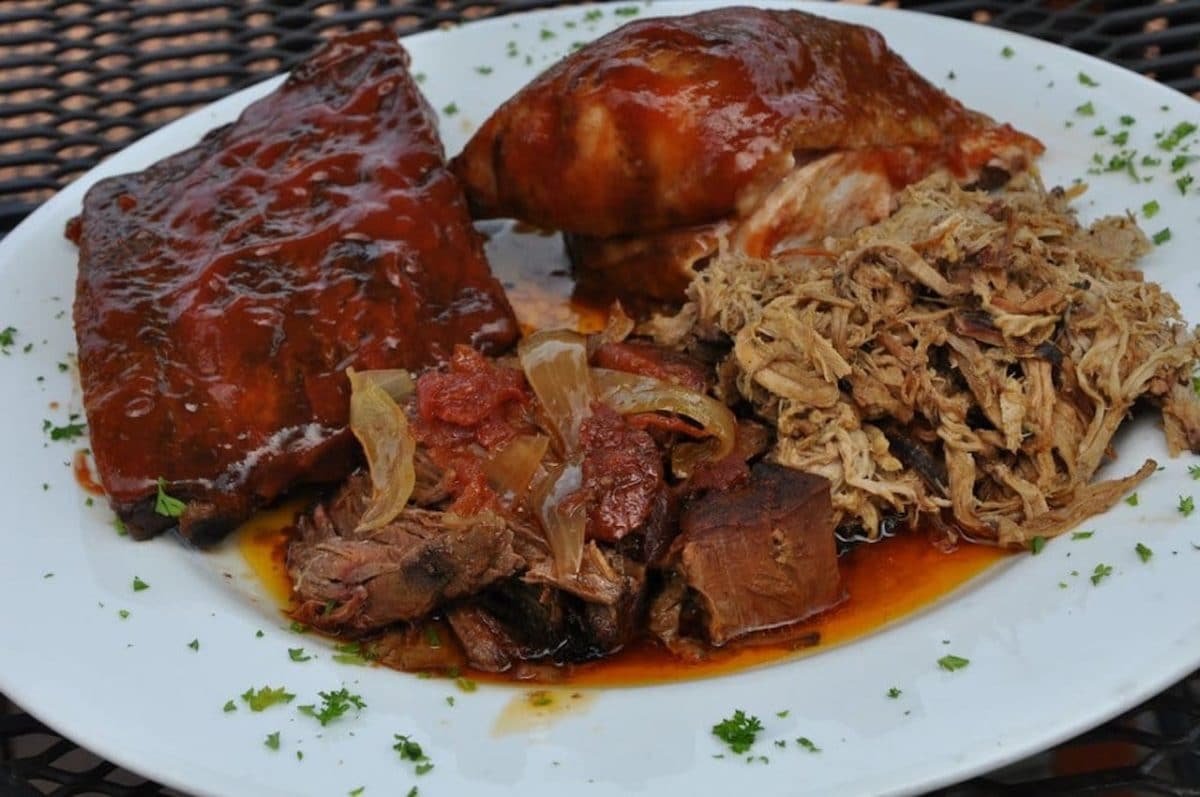 white plate with different types of smoked meats on it in sauce