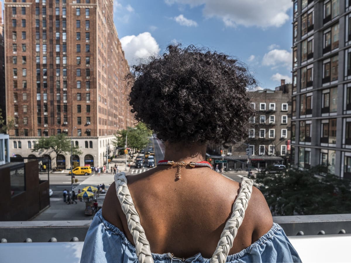 woman standing on high line in nyc and looking out toward the city streets