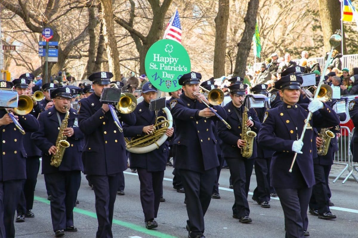 NYPD playing musical instruments and marching with a sign saying "happy st. patrick's day"