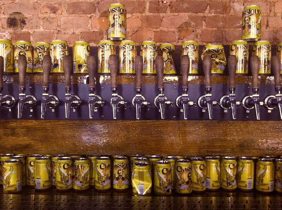 beer taps on wall and beer cans above and below them at bar