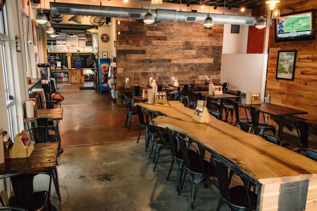 interior of BBQ restaurant with wood tables and tv on wall