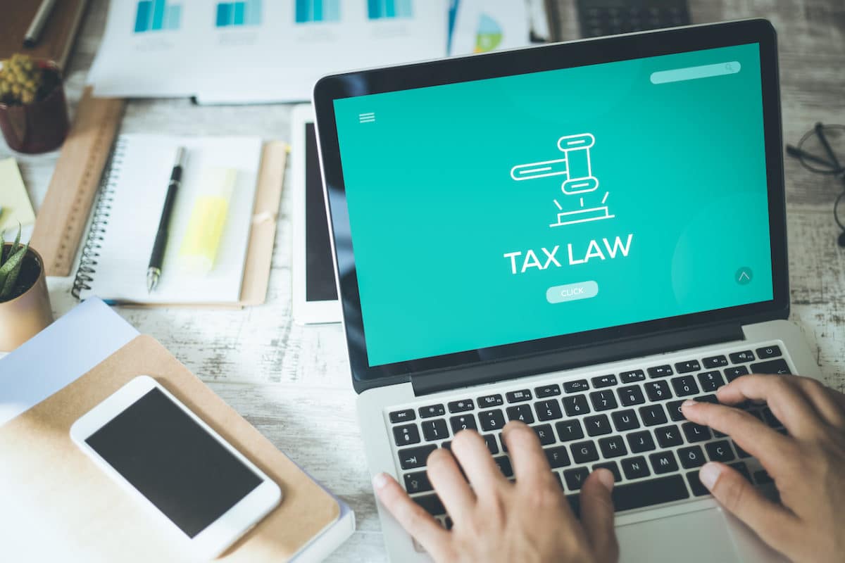 computer with screen reading tax law and person getting ready to type