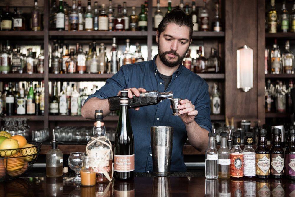 bartender pouring liquor out of a bottle and measuring it for a cocktail at a bar