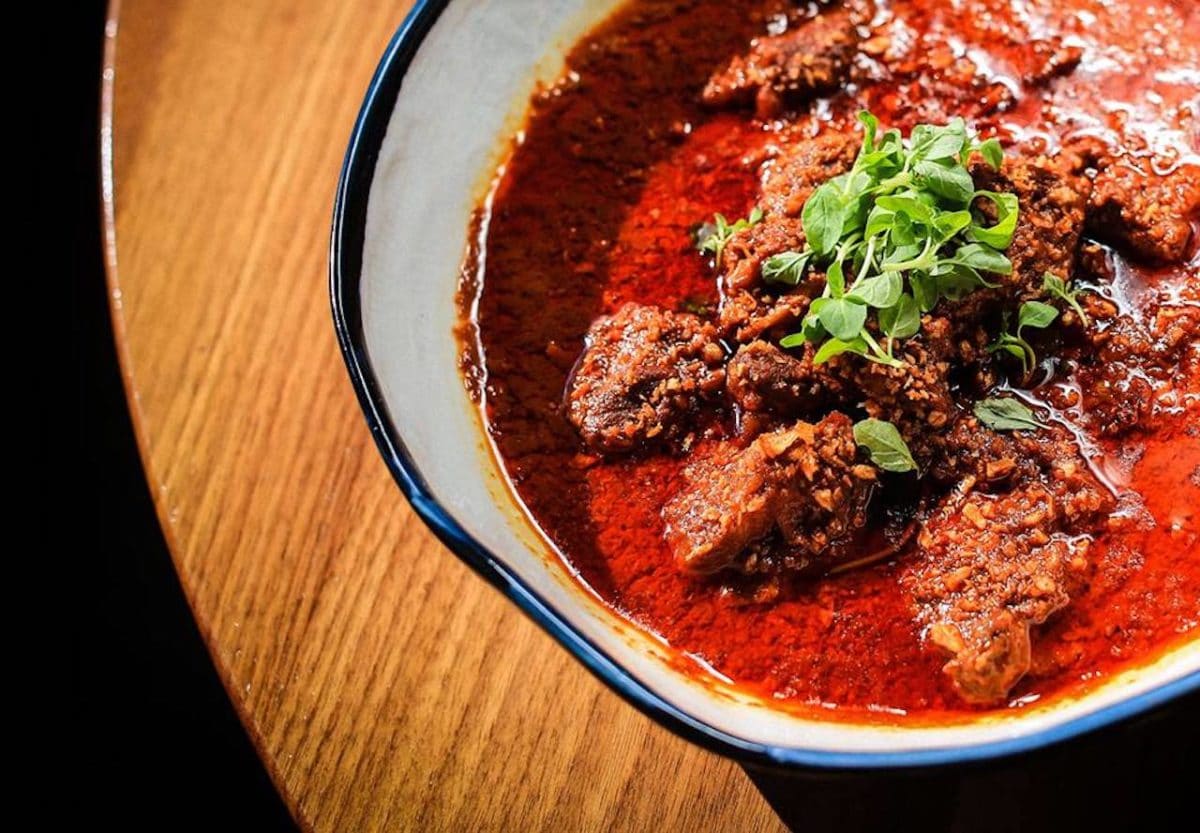 close up of bowl of red sauce and meat with green topping